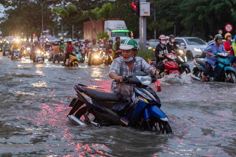CIUDAD HO CHI MINH, VIETNAM - 6 DE NOVIEMBRE: La gente anda en motocicleta por una calle mientras los niveles del agua alcanzan el pico anual el 6 de noviembre de 2025 en la ciudad de Ho Chi Minh, Vietnam. La ciudad de Ho Chi Minh es una de las ciudades costeras que se hunde más rápidamente en el mundo y ha sufrido inundaciones cada vez mayores debido al cambio climático, el aumento del nivel del mar y la rápida urbanización. Según el Banco Mundial, un aumento de 40 cm en el nivel del mar podría causar pérdidas anuales del 1 al 5% del PIB de la ciudad. (Foto de Thanh Hue/Getty Images)