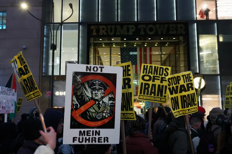 Los manifestantes muestran carteles mientras pasan por la Torre Trump, mientras participan en una protesta contra el conflicto entre Estados Unidos e Israel con Irán.