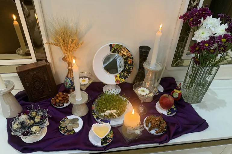 Una vela arde sobre una mesa Haft-Sin, una disposición de siete elementos simbólicos cuyos nombres comienzan con la letra "S"para celebrar las vacaciones de primavera de Nowruz