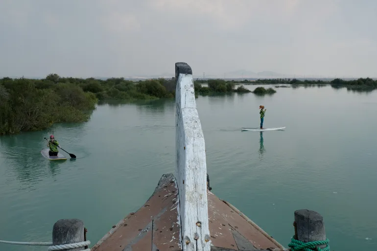 ISLA QESHM, IRÁN - 28 DE FEBRERO de 2021: Dos mujeres en tablas de remo vestidas con trajes especiales para observar el código de vestimenta islámico vistas relajándose en aguas tranquilas del bosque de manglares de Hara el 28 de febrero, en la isla Qeshm, Irán. Los iraníes optan por viajar a las islas del Golfo Pérsico y relajarse debido a las menores restricciones impuestas por el gobierno. (Foto de Kaveh Kazemi/Getty Images)