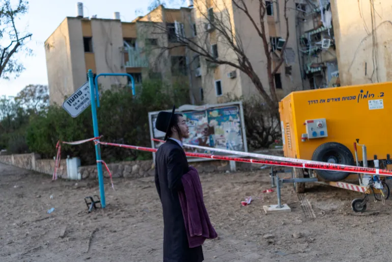Un judío ortodoxo israelí inspecciona el lugar de un ataque con misiles iraníes en Arad el 22 de marzo de 2026.