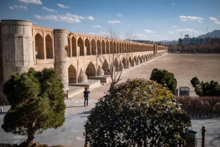 Un hombre iraní se encuentra en la orilla seca del río Zayandeh Rud mientras se muestra una vista del puente histórico Si-o-se-pol (Puente 33) en la ciudad histórica de Isfahán, Irán, el 22 de febrero de 2025. Zayandeh Rud es una de las principales atracciones turísticas de Isfahán, que se ha secado por completo. Puentes históricos como el Puente 33 sobre el río pueden resultar dañados debido al hundimiento del lecho del río Zayandeh Rud si la sequía continúa. (Foto de Morteza Nikoubazl/NurPhoto vía Getty Images)